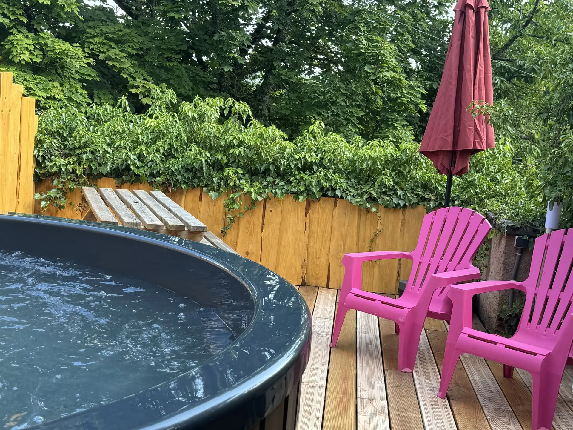 Sièges roses sur une terrasse en bois avec jacuzzi dans un gite en Alsace